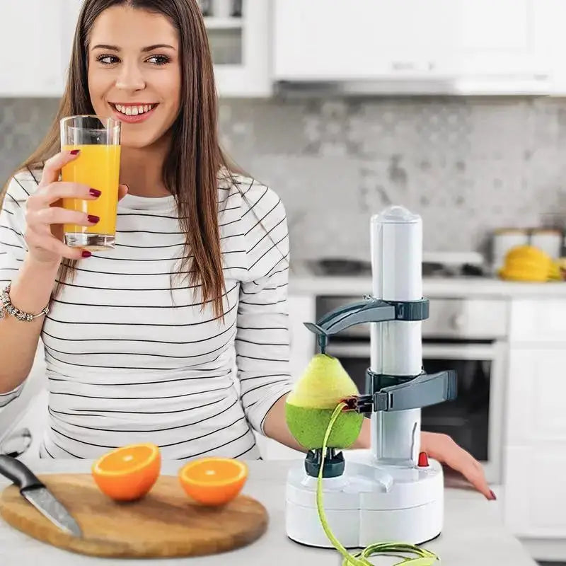 Woman holding a glass of orange juice next to a white electric rotating peeler. Efficient kitchen tool for peeling fruits and vegetables.